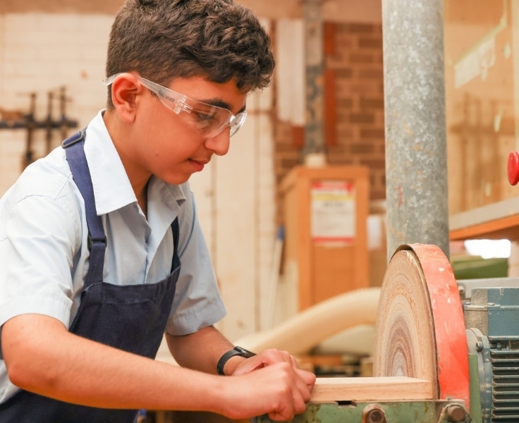 Student using a disc sander in a woodwork room