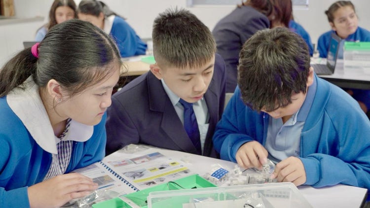 A high school student helping primary school students with robotics